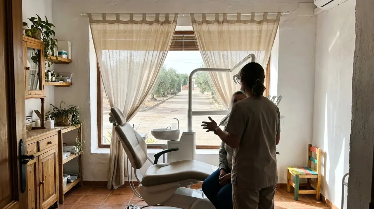 Una de las dentistas atiende a una paciente sentada junto al sillón del gabinete