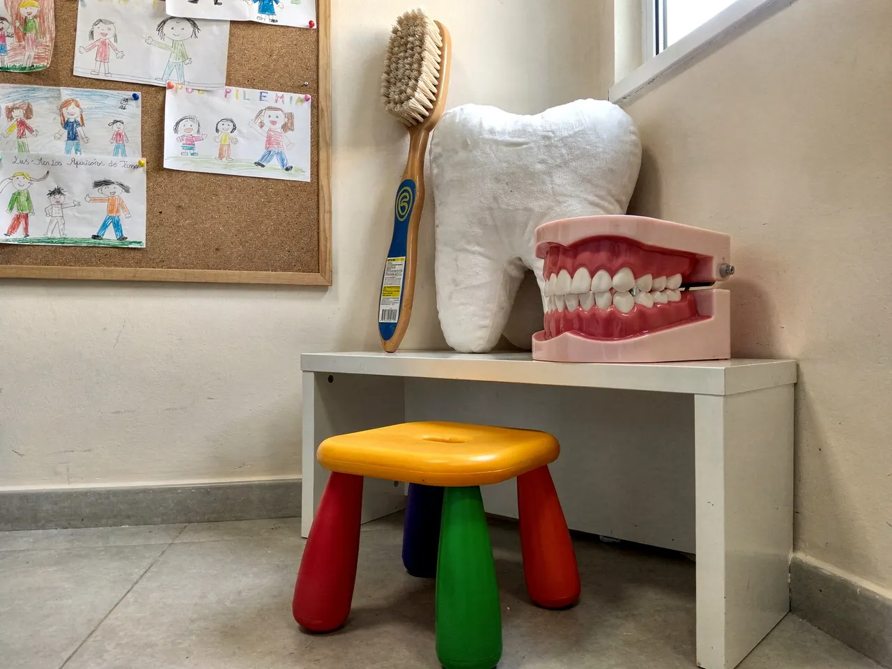 Rincón infantil de la clínica con una muela de peluche y una maqueta dental